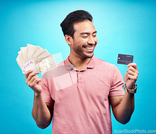 Image of Smile, money and credit card by happy man in studio with savings, finance or investment growth on blue background. Cash, joy and asian guy excited for banking, success or financial freedom isolated