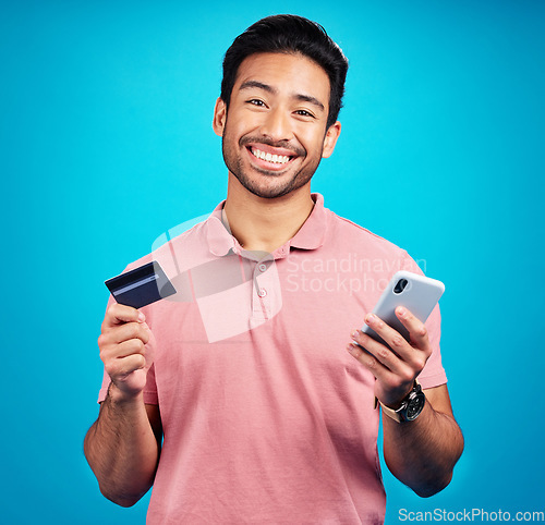 Image of Man with smartphone, credit card and happy in portrait, ecommerce and fintech isolated on blue background. Online shopping, internet banking and finance, technology and male with bank app in studio