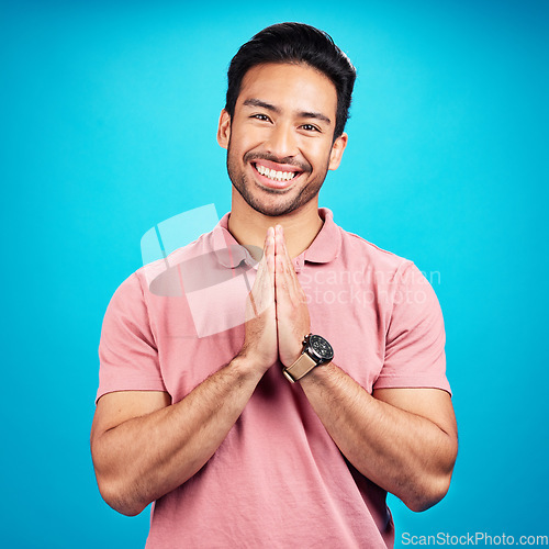 Image of Happy, prayer hands and portrait of a man in a studio with a peaceful, positive and good mindset. Happiness, smile and face of a male model with a grateful hand gesture isolated by a blue background.