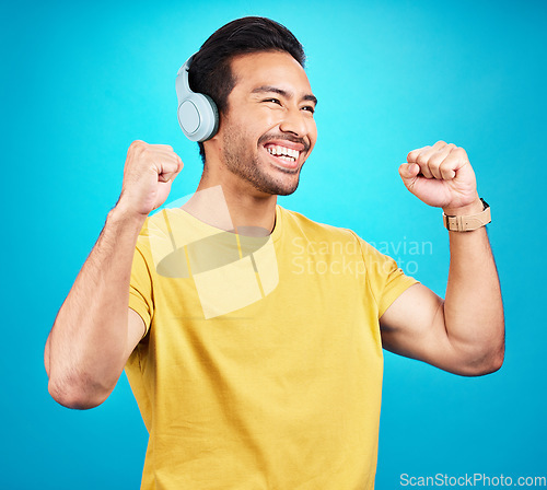 Image of Happy, music and headphones with man in studio for streaming, podcast and dance. Smile, mobile radio and technology with male isolated on blue background for listening, audio and freedom mockup