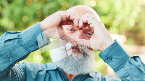 Image of Portrait, hands and heart with a senior man outdoor in a garden during summer for love or health. Face, emoji and shape with a hand gesture by a mature male outside in a park for wellness or romance