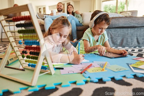 Image of Floor, learning and children with parents relax on sofa for education, creative writing and online digital games at home. Kids on carpet with tablet, headphones and stationery with family on couch