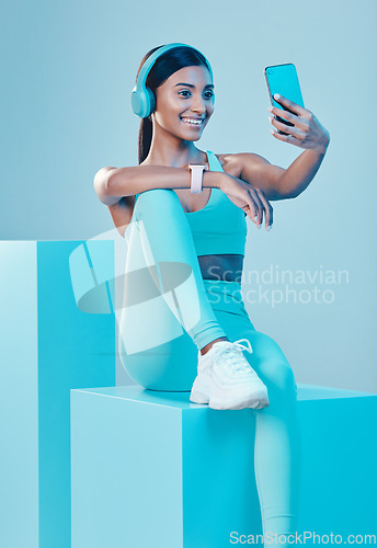 Image of Woman, fitness and selfie in studio with headphones, wellness and training clothes by background. Gen z model, training and fashion with streaming music, body goals or exercise for health by backdrop