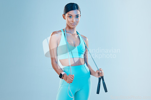 Image of Fitness, skipping rope and mockup with a sports woman in studio on a blue background for health or wellness. Exercise, mindset and space with a young female athlete training for cardio or endurance