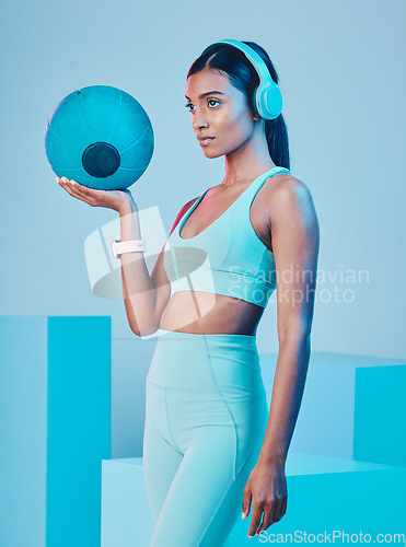 Image of Fitness, ball and woman in studio with music for training, exercise and sports routine on blue background. Headphones, radio and Indian female athlete with weight and podcast, mindset and focus