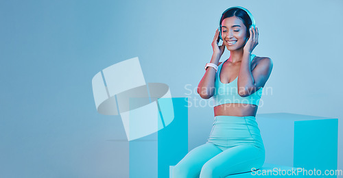 Image of Mockup, fitness and woman with headphones, smile and exercise against a blue studio background. Female model, joy and person with headset, workout and streaming music with happiness, sports and radio