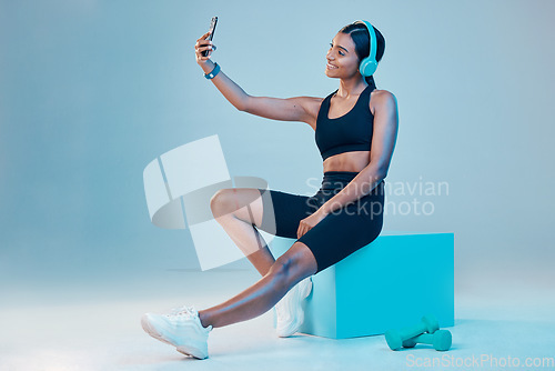 Image of Woman, fitness and selfie in studio with music, wellness or training clothes by background. Gen z model, influencer girl and fashion with streaming, profile picture or exercise for health with smile