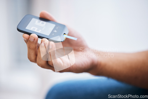 Image of Hand, diabetes and measurement with a man in his home holding a blood glucose meter for disability awareness. Healthcare, medical and sugar with a diabetic male testing insulin levels in his house