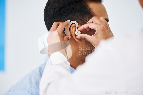 Image of Doctor, man and hearing aid on ear for medical support, wellness and innovation of disability. Closeup, healthcare worker and deaf patient with audiology implant, service and help for sound waves