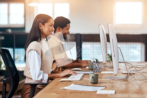 Image of Happy, coworking office and employees at a desk, working together and communication on computer. Smile, our vision and diversity with workers sitting at a table typing on a pc for a corporate job