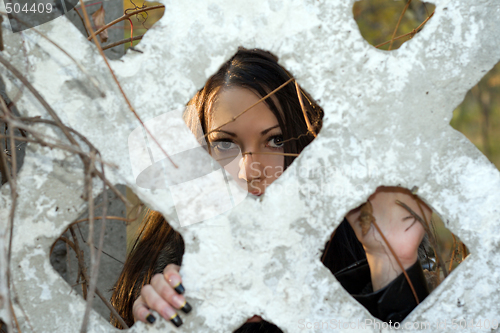 Image of The scared young woman looks through a fence