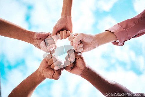 Image of People, hands and fist bump in collaboration, trust or unity for partnership, community or diversity with sky below. Diverse group touching hands for teamwork, success or motivation in solidarity