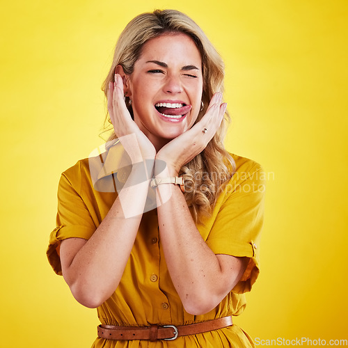 Image of Woman, comic face and sticking out tongue in studio for a funny expression with hands and wink. Female model person being silly on yellow background with a crazy and happy emoji or facial expression