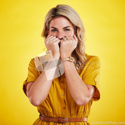 Image of Portrait, shy and woman with fist on face in studio isolated on a yellow background. Female person, introvert and covering mouth with hands, peek and hiding, secret and embarrassed with gossip.