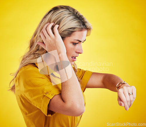 Image of Watch, late and woman checking the time in a studio with a shock, scared and surprise face expression. Panic, anxiety and confused female model with a wristwatch isolated by a yellow background.