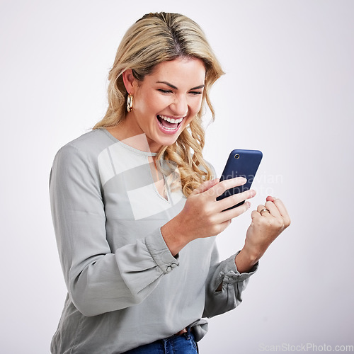 Image of Happy woman, phone and celebration for winning, good news or sale against a white studio background. Excited female with smile on mobile smartphone app in win, discount or bonus promotion and victory