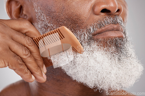 Image of Senior man, hands and beard with comb in grooming, beauty or skincare hygiene against a studio background. Closeup of African elderly male face combing or brushing facial hair for clean wellness