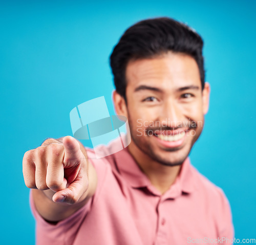 Image of Pointing, focus and portrait of man in studio for motivation, choice and decision. Happy, smile and yes with male and hand gesture isolated on blue background for hey you, offer and emoji mockup