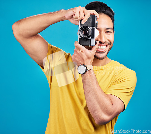 Image of Happy, photographer and man with a camera in a studio for creative or artistic photoshoot. Photography, happiness and portrait of a male person with a hobby for memories isolated by a blue background