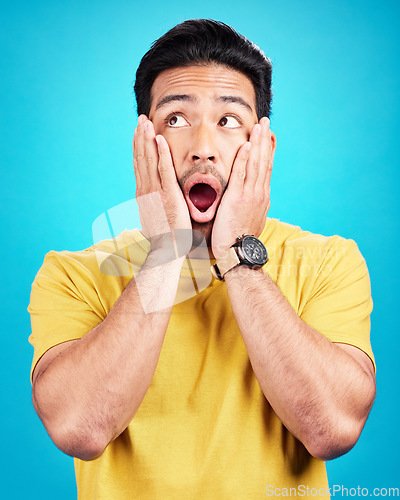 Image of Wow, man and shocked at surprise in studio with announcement, hands on face and mouth open. Male model person on a blue background while scared or thinking of gossip, news or sale with comic emoji