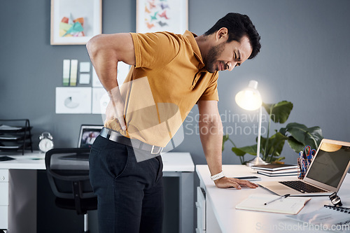 Image of Night, back pain and business man with stress at office desk in a modern workplace. Professional asian male person with health, body ache or burnout problem while tired, injured and working late