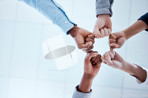 Image of Business people, fist circle and teamwork in low angle, team building and trust in office. Solidarity, huddle and group or staff of men and women with hands together for unity, synergy or cooperation