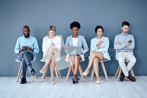 Image of Business people, networking and technology in waiting room for interview, meeting or job search at office. Diversity group of employees sitting in row for recruitment process, collaboration or hiring