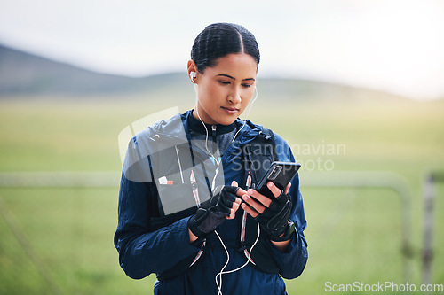 Image of Music, phone check and woman in the countryside ready for fitness and exercise. Sports, training and mobile headphones of a female athlete looking at gps with audio and web radio for workout