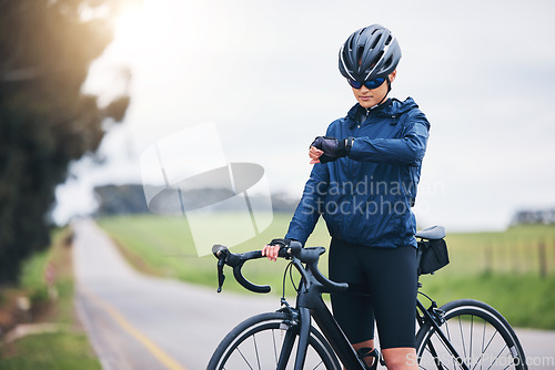 Image of Cyclist woman, check time and nature on road for speed, gps and heart rate with fitness, health and wellness goal. Cycling, bicycle and female athlete with watch for exercise, training and workout