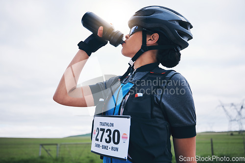 Image of Fitness, cyclist or woman drinking water in park to hydrate, relax or healthy energy on exercise break. Tired thirsty girl athlete biker refreshing with liquid for hydration in training or workout