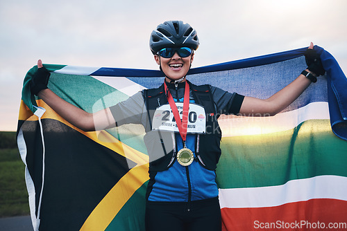 Image of Winner sports, happy woman from South Africa with flag and gold medal winning, outdoor cycling race or triathlon. Happiness, win and cyclist with smile, fitness and world record with national pride.