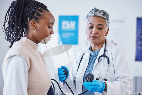 Image of Consultation, doctor and patient with blood pressure test and healthcare advice at clinic. Black woman consulting female medical professional, health care check and expert support or help at hospital