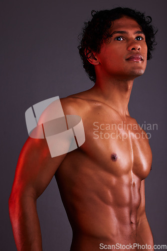 Image of Light, strong and man chest in a studio with art lighting and thinking with muscles and fitness. Focus, isolated and gray background of an attractive male model with artistic, and shirtless spotlight