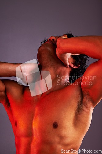 Image of Red light, body and man in a studio with art lighting and wellness with muscles and fitness. Neon, isolated and gray background of attractive and strong male model with artistic, sensual and creative