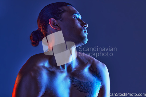 Image of Man, sexy body and light in studio for art, fitness or beauty of a person on a blue background. Face, strong chest and fitness model with a tattoo, glow and creative motivation for aesthetic backdrop