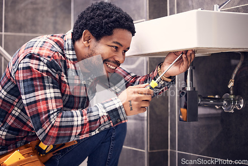 Image of Happy, man or plumber fixing a sink with smile in maintenance or installation in home repairs. African handyman or worker with plumbing tools to fix water pipes or house basin in renovation project