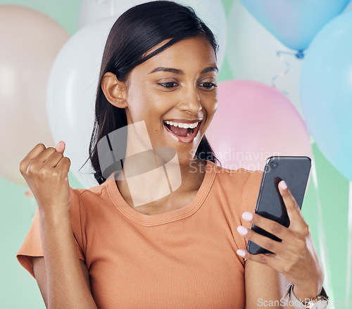 Image of Winner, phone and happy woman with party balloons for birthday celebration, prize or online giveaway success or news. Yes, fist pump and wow of indian person bonus, lotto or winning deal in studio