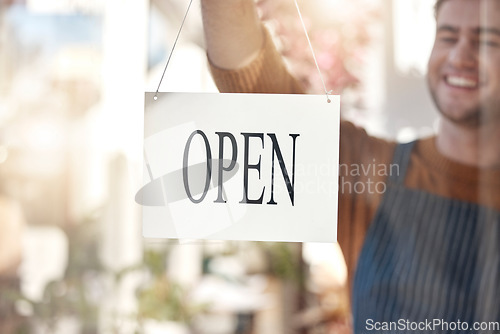 Image of Happy owner, open sign and small business ready for service, customer help or advertising at store. Man waiter smiling at entrance setting up shop or opening label, poster or billboard at cafe