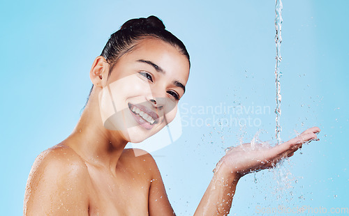 Image of Water drops, skincare and portrait of woman with smile for health, wellness and hygiene with cleaning routine. Shower, cosmetic beauty and happy girl in skin care for hands on blue studio background.