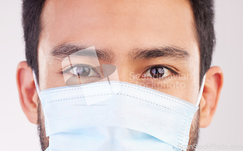 Image of Doctor, portrait and man with mask for covid, compliance and safety in studio closeup. Facemask, prevention and eyes of male health expert at a clinic for help, treatment and healthcare control