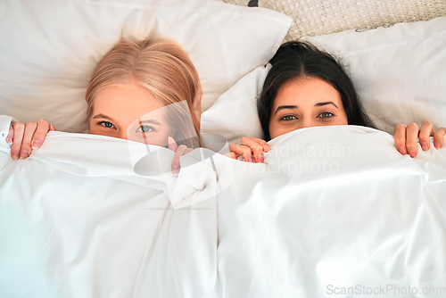 Image of Above, portrait and women covering with blanket for hiding, shy and cold in a bed. Sleep, relax and friends with a duvet to cover face for happiness, funny and warmth in the bedroom together