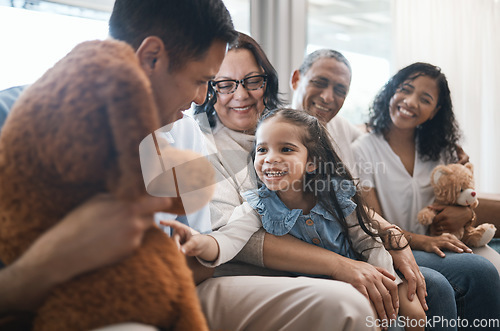 Image of Big family, parents and girl with teddy bear on couch, grandparent and smile for game in home living room. Men, women and female child with toys, love and happiness on lounge sofa in house on holiday