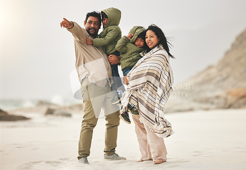 Image of Family, children and parents at the beach in winter for quality time, love and care outdoor in nature. Man, woman and kids on a vacation, holiday or travel trip for bonding and pointing at sea