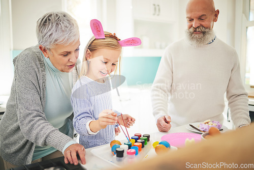 Image of Easter, art and a girl painting with her grandparents in their home for love, bonding or celebration together. Family, kitchen or egg with a senior couple and their grandchild in a house to paint