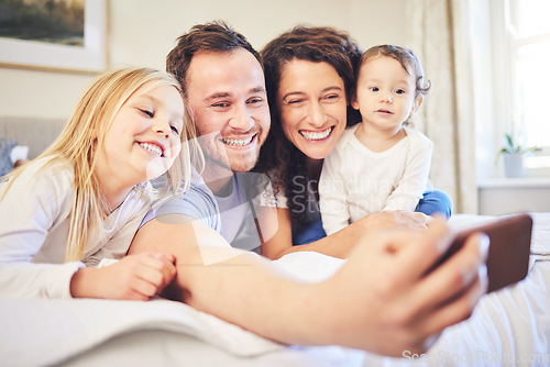 Image of Family, selfie and smile in a home bedroom with children and parents together on bed for quality time. Man and woman of mother and father with children for a happy profile picture or memory for love