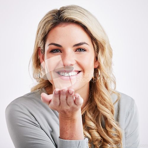 Image of Portrait, love and blowing a kiss with a woman in studio on a gray background for romance or affection. Face, hand gesture and kissing with an attractive young person smiling on valentines day