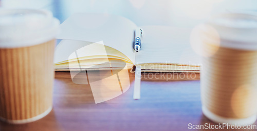 Image of Notebook, coffee or planning with cups, a pen and a book on a table or desk in an empty office boardroom. Business, meeting and strategy with still life stationery on a wooden surface in a workplace