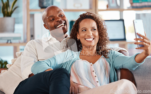 Image of Selfie, happy and couple with smile on sofa for bonding, quality time and relaxing together at home. Marriage, happiness and interracial man and woman take picture for social media, memory and post