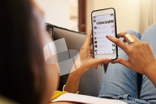 Image of Closeup of woman on her smartphone lying on a sofa, relaxing in a bright living room. A young latino female relaxing and texting on her cellphone using modern technology at home