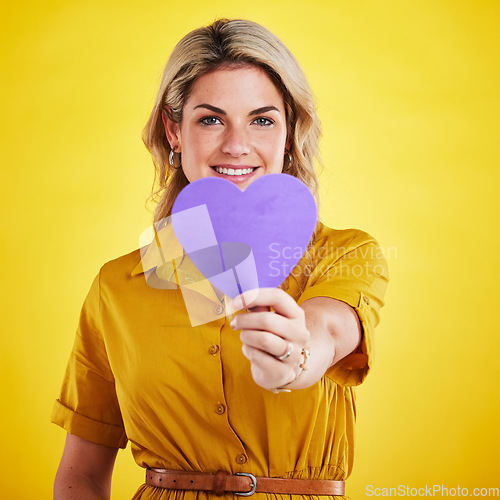 Image of Portrait, cut out heart and woman with support, smile and wellness against a studio background. Face, female person and model with a symbol for love, paper and sign with happiness, romance and loving